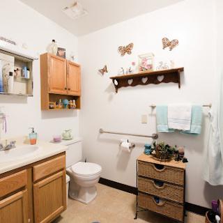 A cozy bathroom featuring wooden cabinets, decorative butterflies, and organized storage.