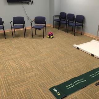 A meeting room equipped with chairs, a television, and a putting mat on the floor.