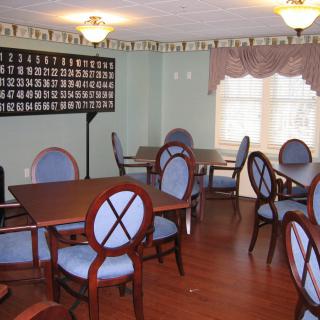 A dining area with neatly arranged tables and chairs, featuring large windows and elegant lighting.