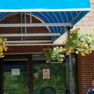 A building entrance with a blue awning and hanging flower baskets.