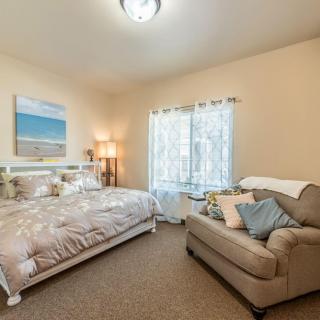 A cozy bedroom with a bed, sofa, and soft lighting.