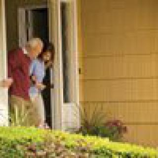 An elderly couple stepping out of their home.