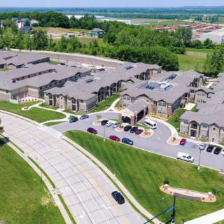 Aerial view of a suburban apartment complex surrounded by greenery and roads.