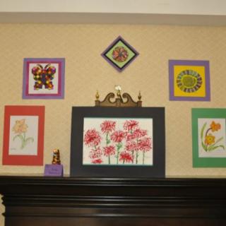 A collection of colorful framed artworks featuring floral designs displayed on a wall.