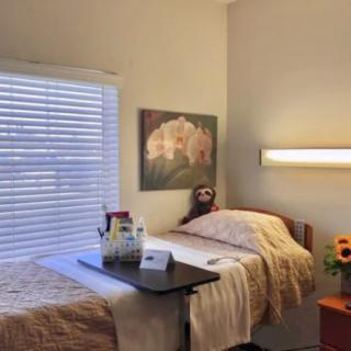 A cozy bedroom with a single bed, side table, and a window with blinds.
