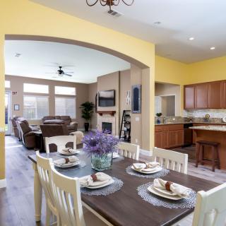 A beautifully designed open floor plan featuring a dining area with a set table, leading into a cozy living room and a modern kitchen.