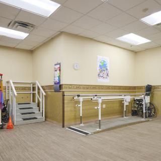 A physical therapy room equipped with parallel bars and stairs for rehabilitation exercises.