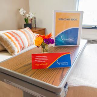 A welcoming hospital patient room setup featuring a table adorned with flowers and informational materials.