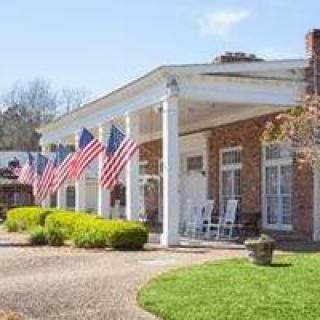 A brick house with a large front porch adorned with multiple American flags.