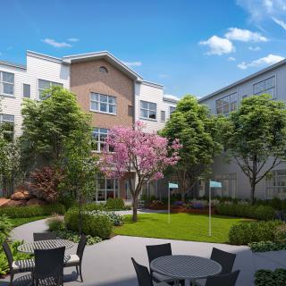 A modern apartment building with a landscaped garden and outdoor seating.