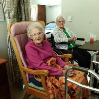 Two elderly women enjoying each other's company in a care facility.