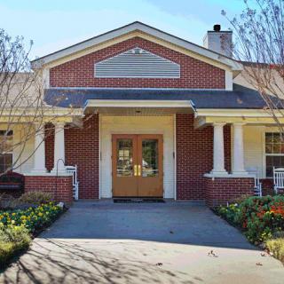 A brick building with a welcoming entrance featuring white columns and a landscaped pathway.