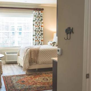 A cozy bedroom with a patterned rug, curtains, and soft lighting.