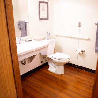 A clean and accessible bathroom featuring a toilet, sink, and handrails.