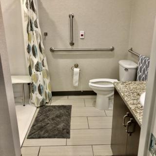 An accessible bathroom with a shower, grab bars, and tiled flooring.