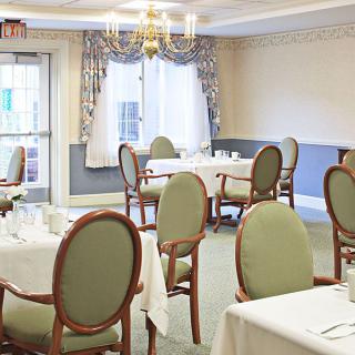 An elegantly furnished dining room with multiple tables and chairs arranged neatly under a chandelier.