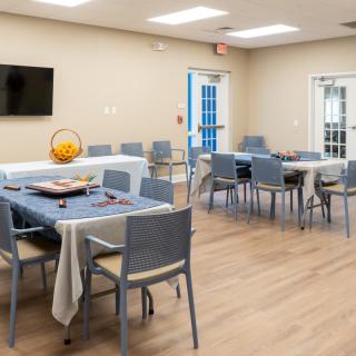 A modern dining area with arranged tables and chairs, featuring a wall-mounted television.
