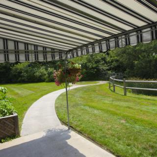 A scenic garden pathway under a covered structure, surrounded by lush greenery.
