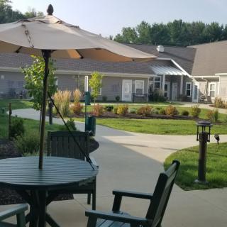 A peaceful patio area with chairs and an umbrella, surrounded by a landscaped garden.