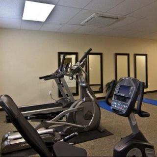 A gym with exercise equipment including treadmills and a stationary bike, along with mirrors on the walls.