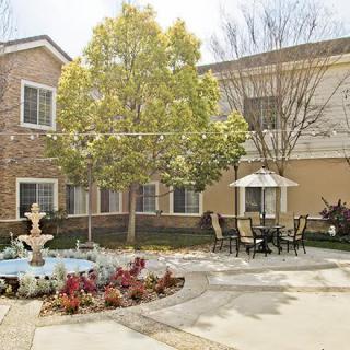 A tranquil courtyard featuring a fountain, outdoor seating, and lush landscaping.
