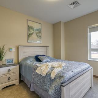 A cozy bedroom with a neatly made bed, a nightstand, and artwork on the wall.