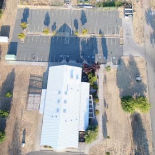 Aerial view of a building with a large parking lot, casting long shadows in the afternoon sun.