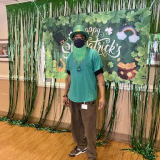 A festive celebration for St. Patrick's Day, featuring a man dressed in green standing in front of themed decorations.
