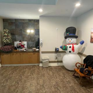 A cozy holiday-themed interior featuring a cheerful snowman, a beautifully decorated Christmas tree, and festive decorations.