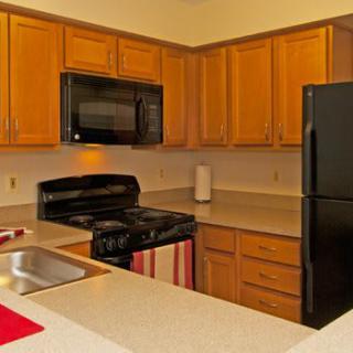 A modern kitchen featuring wooden cabinets, a black stove and microwave, a sink, and a black refrigerator.