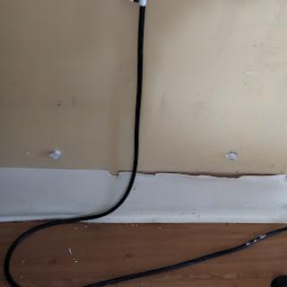 A black cable running along the wall and baseboard of an interior space.