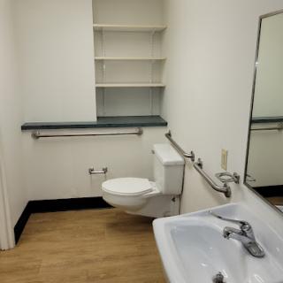A clean and simple bathroom with a toilet, sink, and shelves.