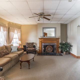 A cozy living room with a fireplace, sofa, and ceiling fan.