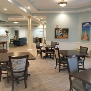 A spacious dining area with neatly arranged tables and chairs, adorned with artwork and soft lighting.