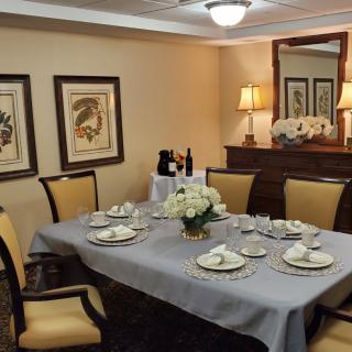 An elegantly set dining room table with fine dinnerware and a centerpiece, surrounded by classy decor.