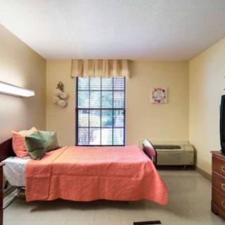 A cozy and well-lit bedroom featuring a neatly made bed with colorful bedding and a window that brings in natural light.