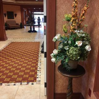 A view of a hotel lobby featuring a floral arrangement on a pedestal.