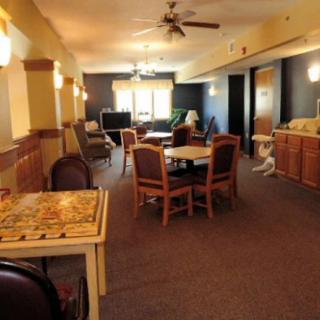 A cozy indoor dining area with multiple tables and chairs, featuring a ceiling fan and carpeted floor.
