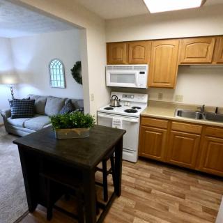 A cozy kitchen with wooden cabinets and an adjacent living room featuring comfortable furniture.