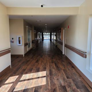 A well-lit corridor with wooden flooring and doors on either side.