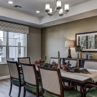 A neatly arranged dining room with a table set for dinner, featuring elegant chairs and a stylish chandelier.
