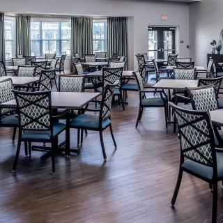 An empty dining area with neatly arranged tables and chairs on a hardwood floor.