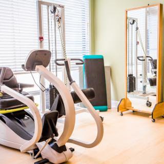 A modern rehabilitation gym featuring specialized exercise equipment and a mirror.