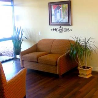A cozy waiting area with a sofa, plants, and artwork on the wall.