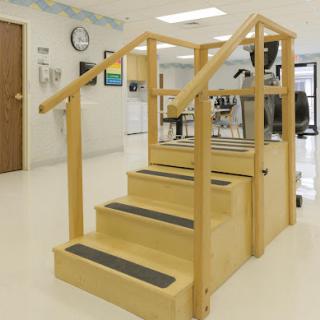 A wooden staircase with handrails designed for rehabilitation and physical therapy.