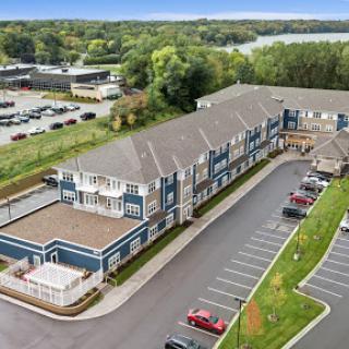 Aerial view of a modern hotel with a spacious parking lot surrounded by greenery.