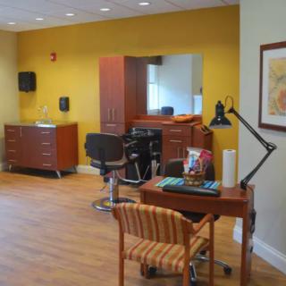 A brightly lit hair salon interior with chairs, a mirror, and a desk.