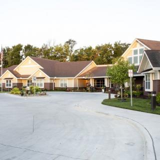 A nursing home building with a driveway and surrounding greenery.