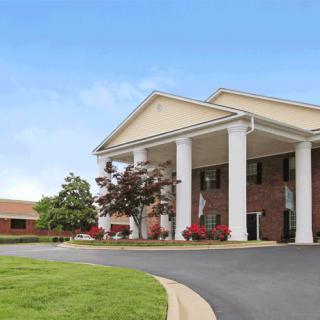 A large brick building with prominent white columns and a landscaped driveway.