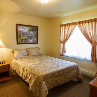 A cozy bedroom with a double bed, lamp, and window with curtains.